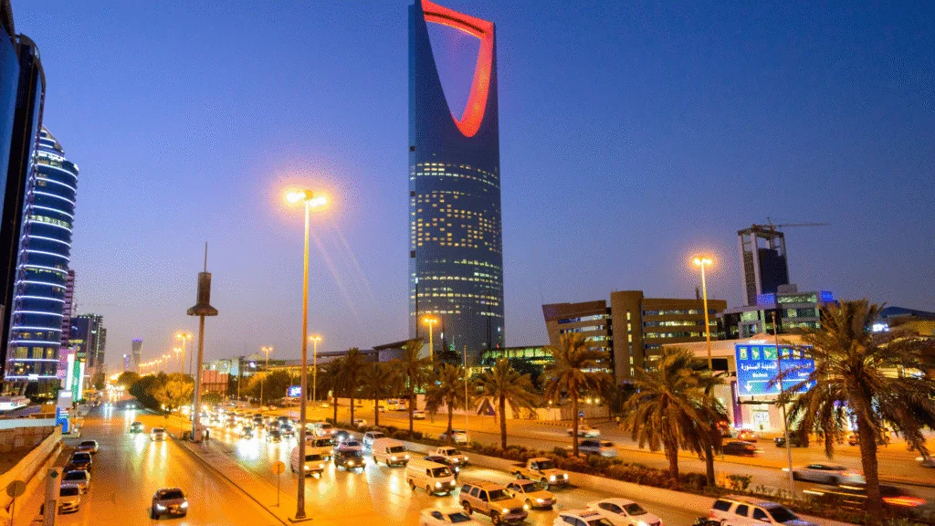 Riyadh skyline at dusk with the illuminated Kingdom Centre Tower and vibrant city traffic – Apartment for Rent in Riyadh for Expatriates